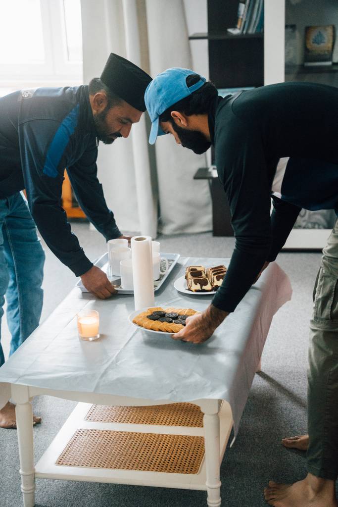 Männer tragen Tablett mit Tee und Kuchen herein